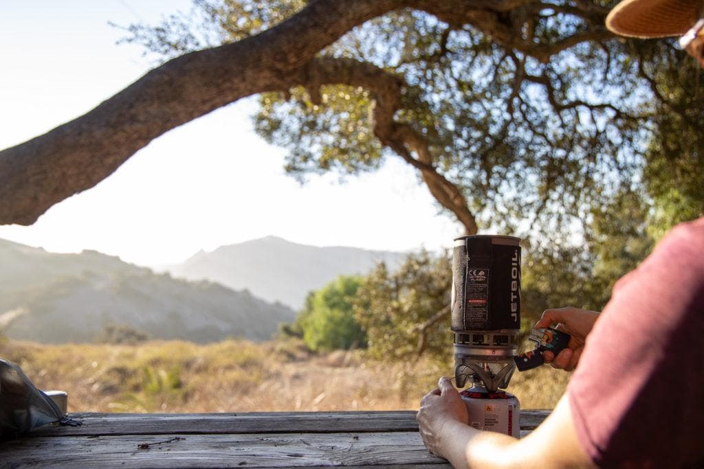 A woman boils water on a backpacking trip using a JetBoil