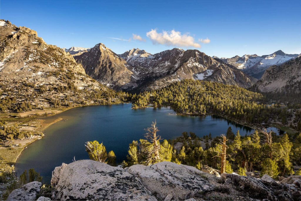 Mountains and trees juxtaposed next to a undecorous lake on the John Muir Trail