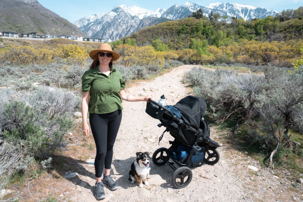 Women hiking on a flat trail with a stroller and a mini Australian shepherd wearing the Oboz Katabatic hiking shoe