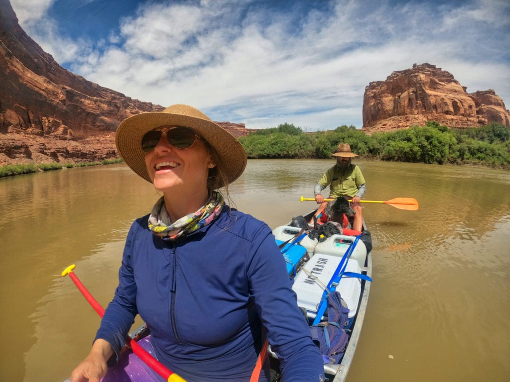 Two people in a canoe on the Green River in Utah surrounded by red rock landscape