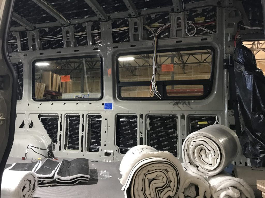 Interior of cargo van ready for insulation installation. Rolls of wool insulation on the floor. 