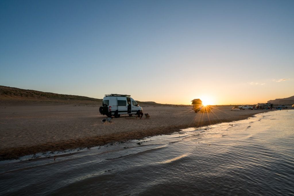 Sprinter Van parked on the beach at sunset at Lone Rock campground at Lake Powell