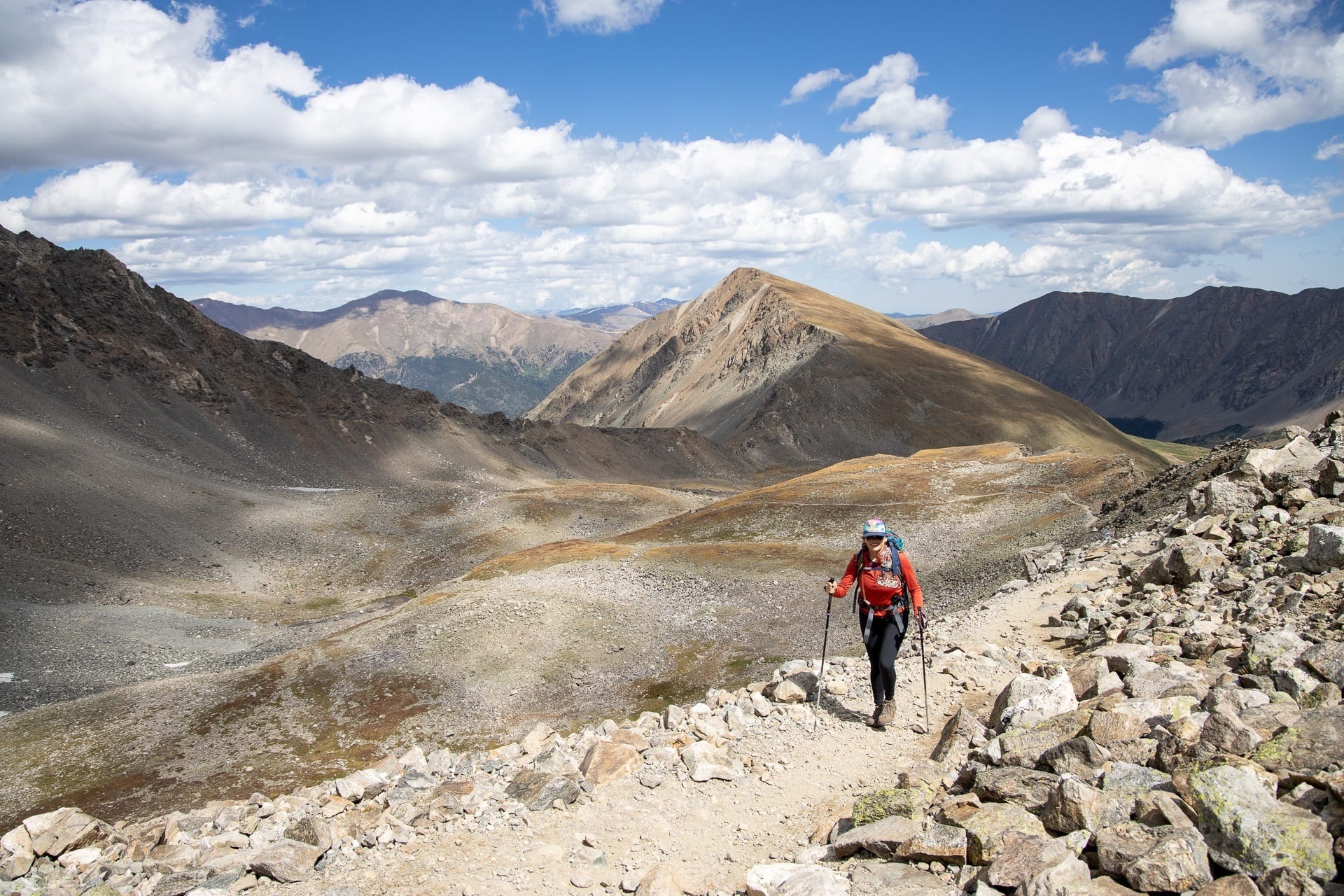 Kristen Bor hiking on high alpine trail in Colorado using trekking poles and wearing hiking gear