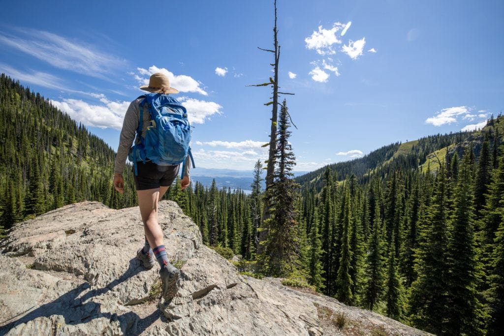 A woman hikes up a rocky path with a daypack on