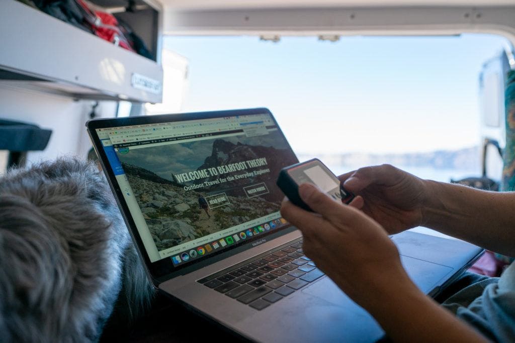 A close up of a Verizon Mifi mobile hotspot next to an open laptop working in a campervan