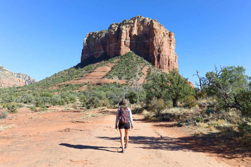 Woman hiking down trail in Sedona with Courthouse Butte in front of her