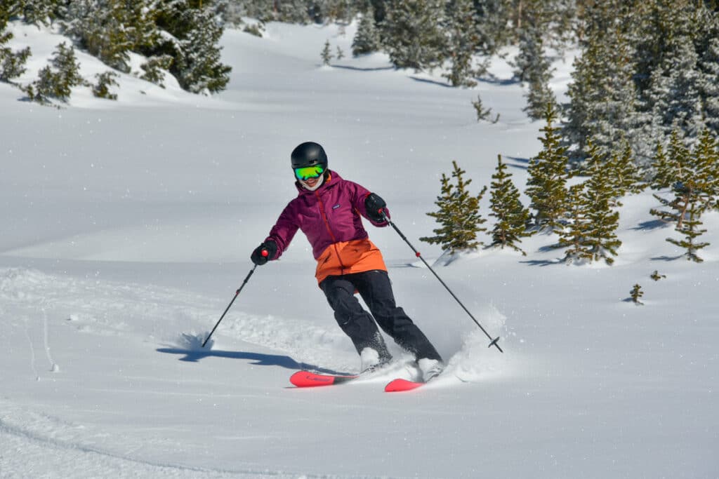 Bearfoot Theory founder Kristen Bor skiing powder wearing a pink Patagonia jacket at irwin lakes in Crested Butte Colorado