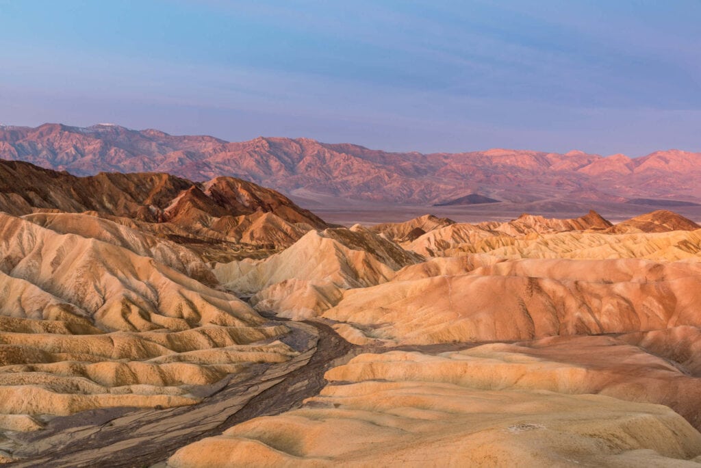 Landscape view of Death Valley's bandlands with mountain range in distance at dusk