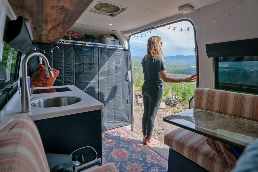 Kristen Bor inside a Sprinter Van looking out the slider door