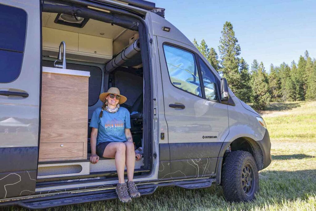 Bearfoot Theory founder Kristen Bor sitting in the doorway of her Sprinter Van