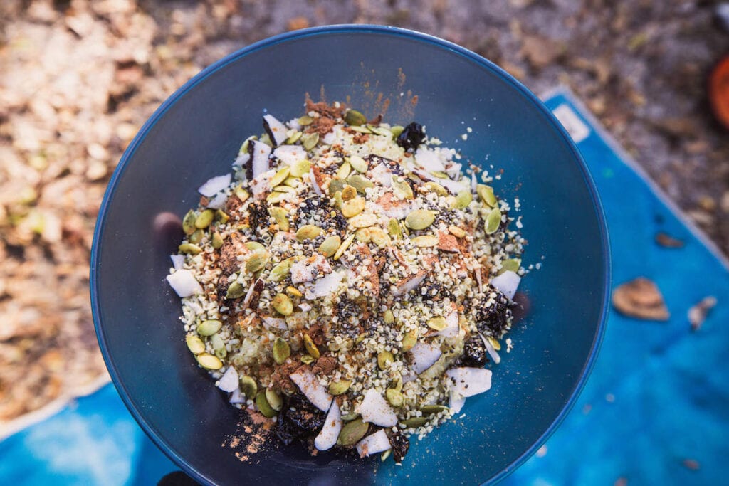 Close up shot of a quinoa breakfast bowl with pumpkin seeds, coconut flakes, cinnamon, and other toppings