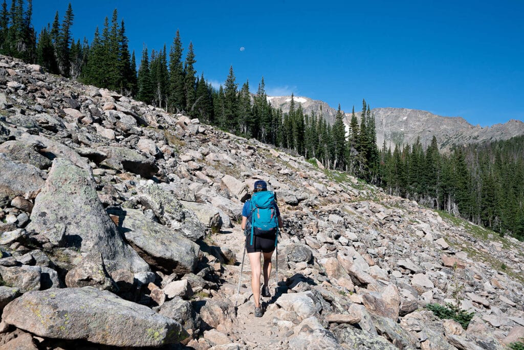 Woman hiking along a rocky trail // keep a hiking first aid kit on you in case of emergency