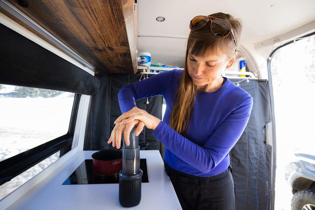 A woman presses down on the Aeropress Go travel coffee press