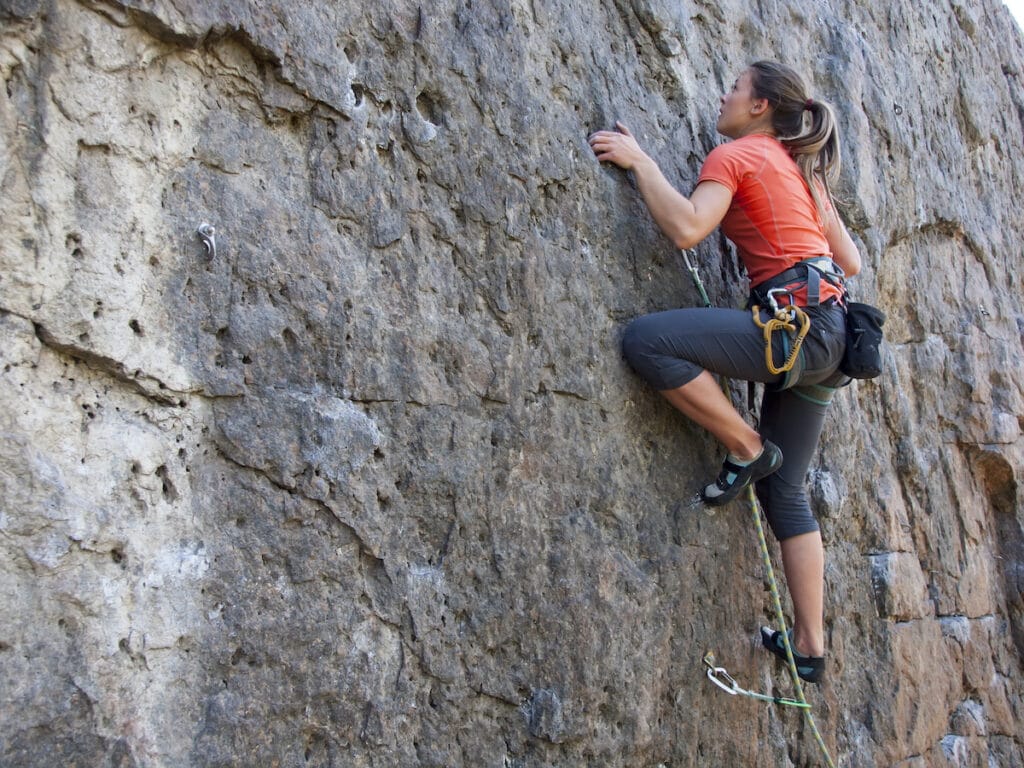 A woman rope climbing on rock cliff face