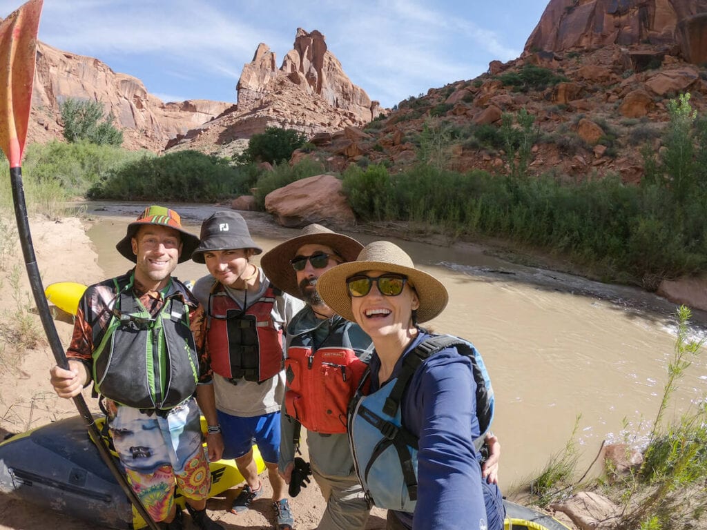 3 men and 1 woman smiling for a selfie along a river