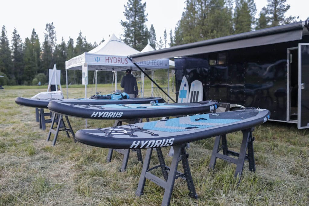 Three paddle boards out of the water resting off the ground on racks