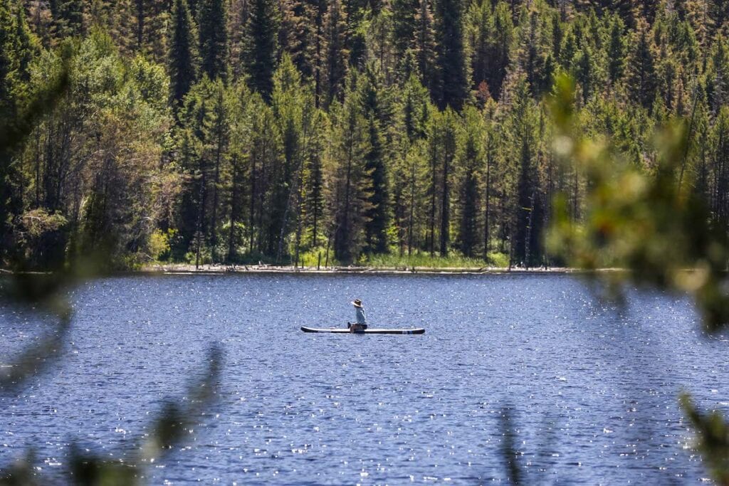 Woman kneeling on a paddle board on a lake 