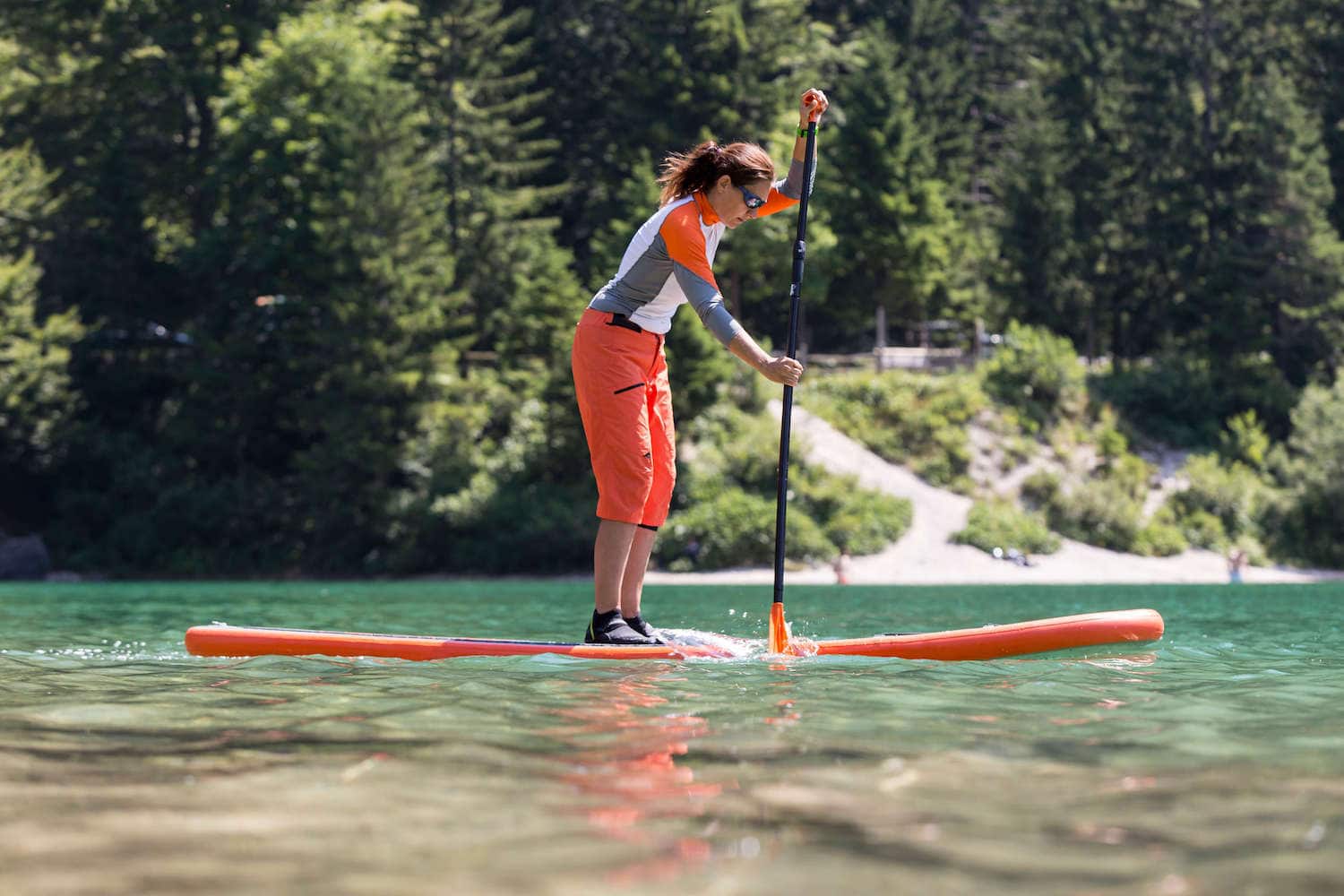 Woman standing on paddle board paddling in calm water