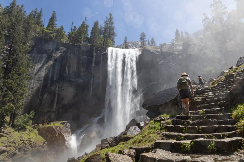 Hiker walking up rock stairs next to Vernal Falls on the Mist Trail in Yosemite