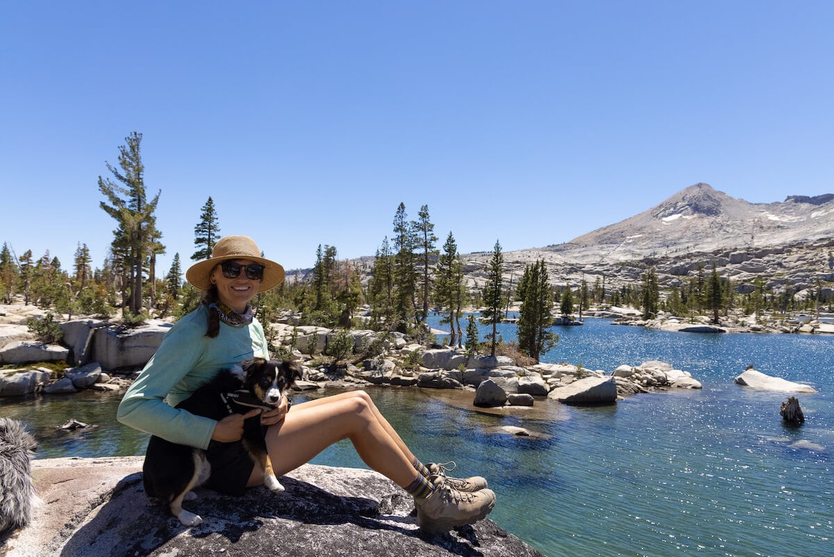 A woman sits at Lake Aloha Desolation Wilderness with her dog