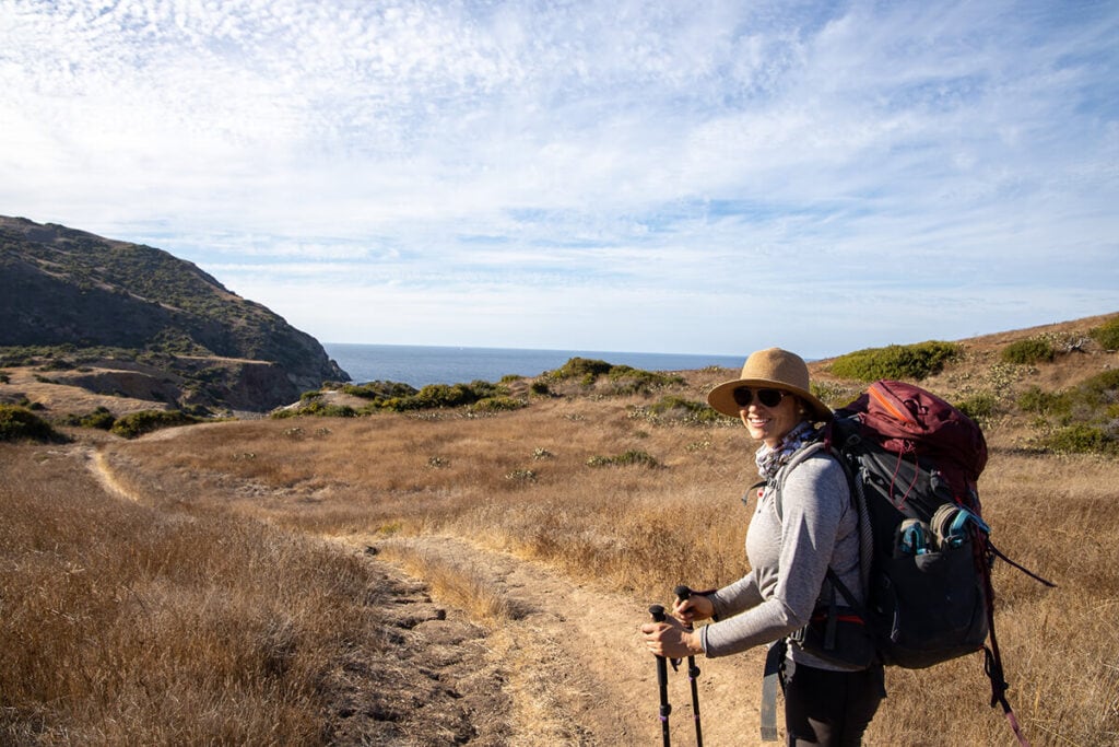 A woman smiles on the Trans-Catalina Trail wearing a backpacking pack