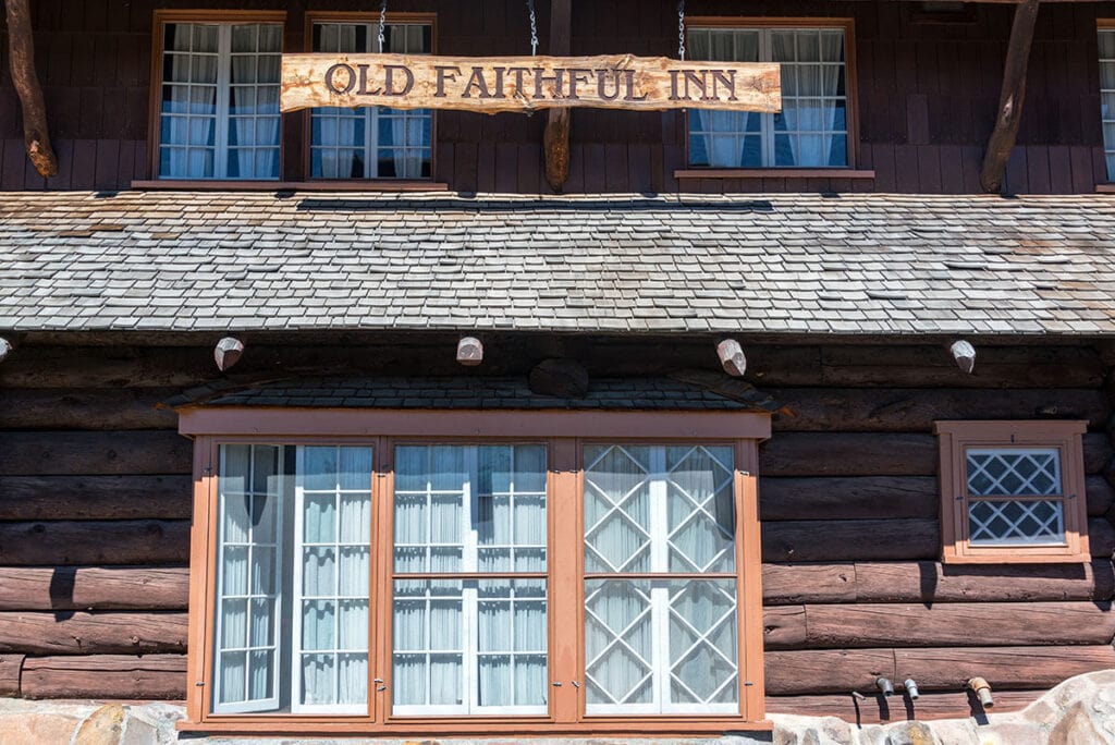 Photo of the front of Old Faithful Lodge with sign hanging from eaves