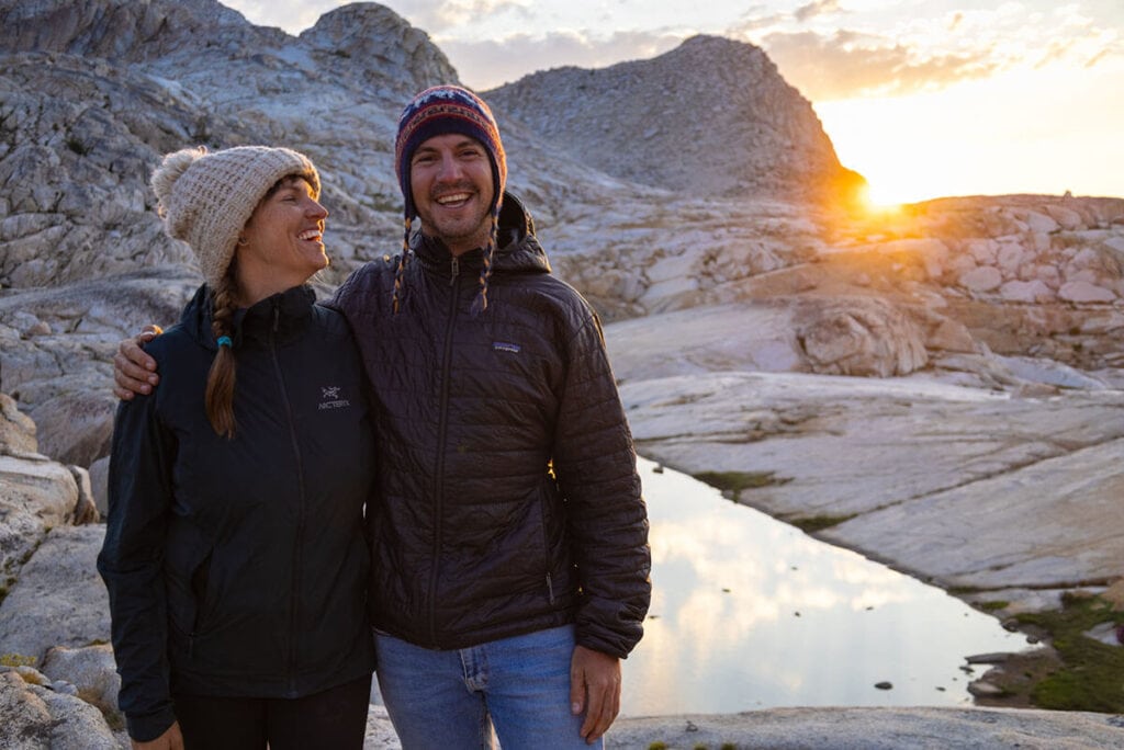 a man and woman smiling wearing Arc'teryx Atom ST and Patagonia Nano Puff synthetic down jackets on a backpacking trip in Sequoia National Park at sunset