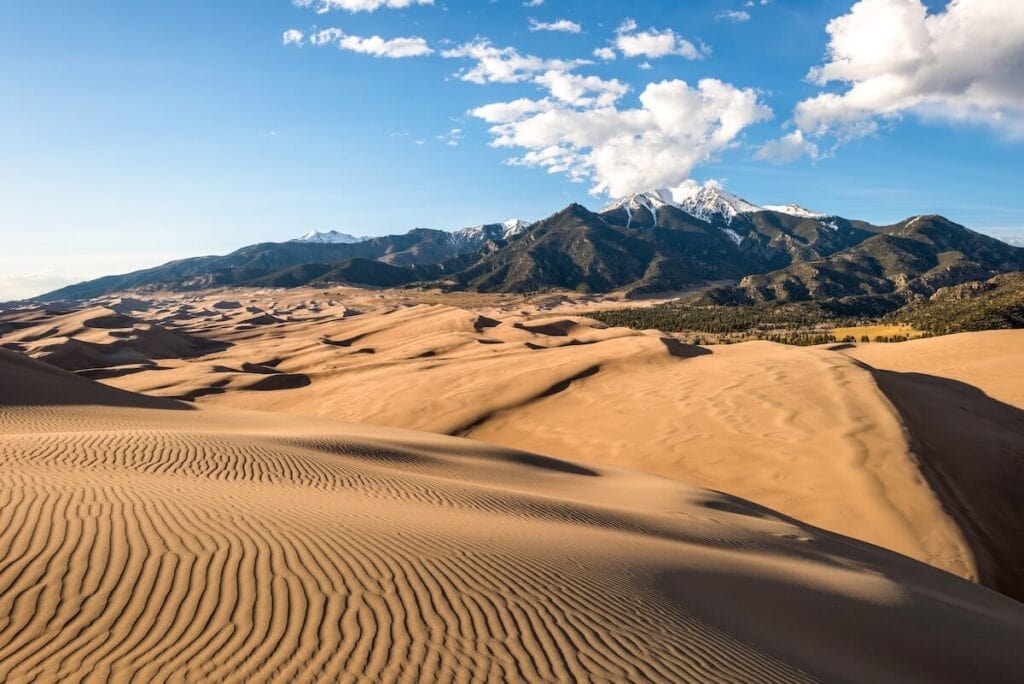 Great Sand Dunes National Park in Colorado with Rocky Mountain Peaks rising up behind dunes