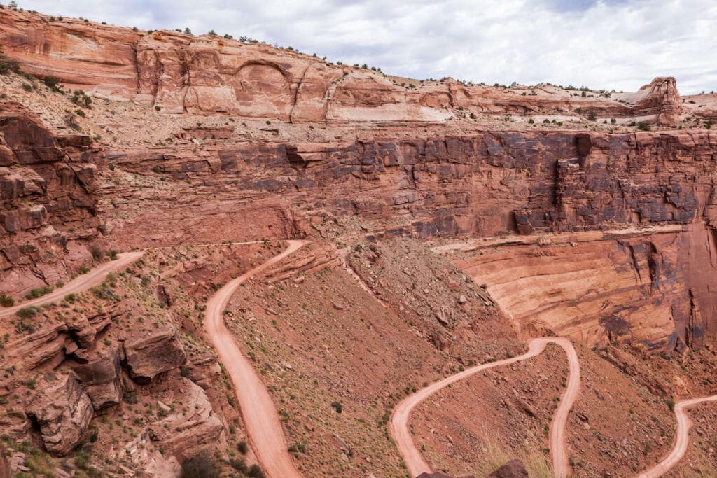 Winding Shafer switchbacks leading down a steep red rock bluffs on the White Rim Trail in Moab