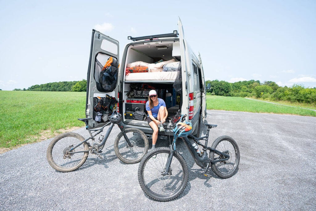 Kristen with mountain bikes outside the back of her van // Learn about Progressive RV insurance, including what types of vehicles are covered, different coverage options, & tips for insuring your van.