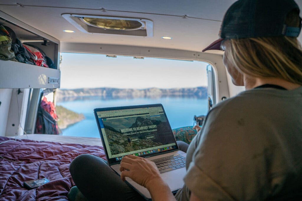 Kristen working on her laptop in the Sprinter van // Learn about Progressive RV insurance including what vehicles are covered, different coverage options, & tips for insuring your camper van.