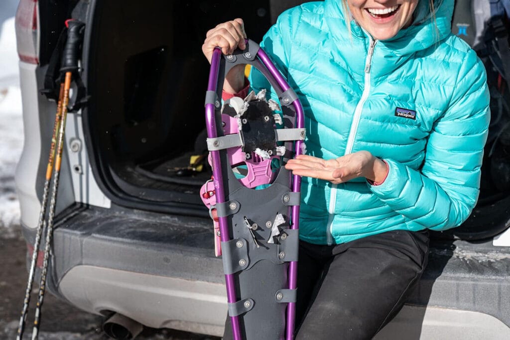 A woman points to the sharp crampons on the bottom of Yukon Charlie's Advanced Float snowshoes