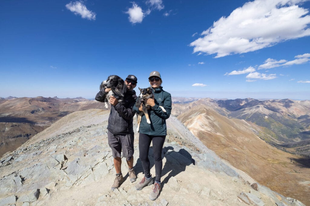 man and woman hiking in Colorado with two dogs // marijuana intoxication in dogs while hiking is becoming a big problem