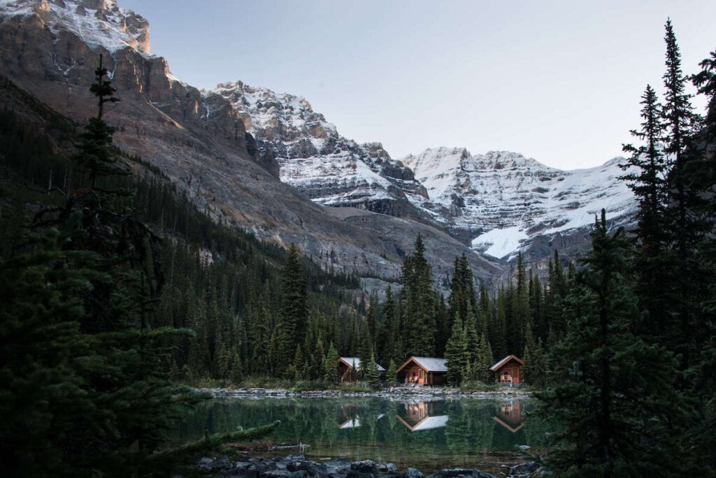 Lake O'hara lodge cabins overlooking scenic alpine lake in Yoho National Park, British Columbia with snow-capped mountains in background