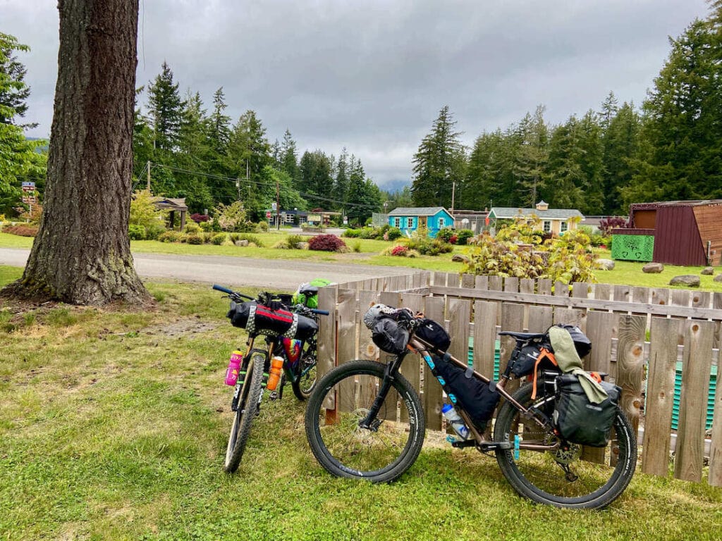 Two bikes resting on a wooden fence surrounded by a few houses