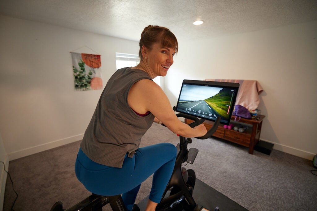Woman spinning on indoor cycling bike wearing the lululemon Train To Be Tank