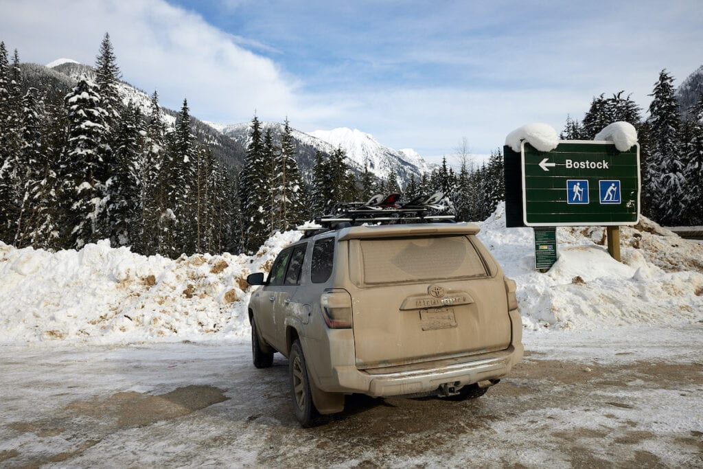 Toyota 4runner covered in dirt with snowy mountains in background near Rogers pass on British Columbia's Powder Highway