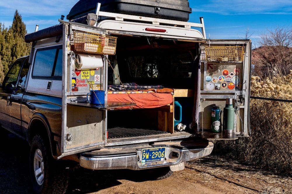 Rear access to truck camper with both doors open to the sides, showing platform bed and living space