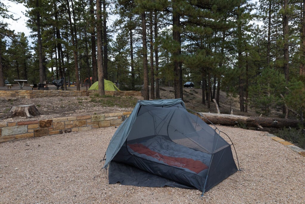 Tent set up on flat gravel campsite in forested area