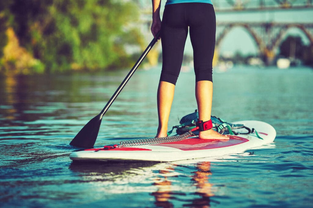 Woman standing on a paddle board on flat water