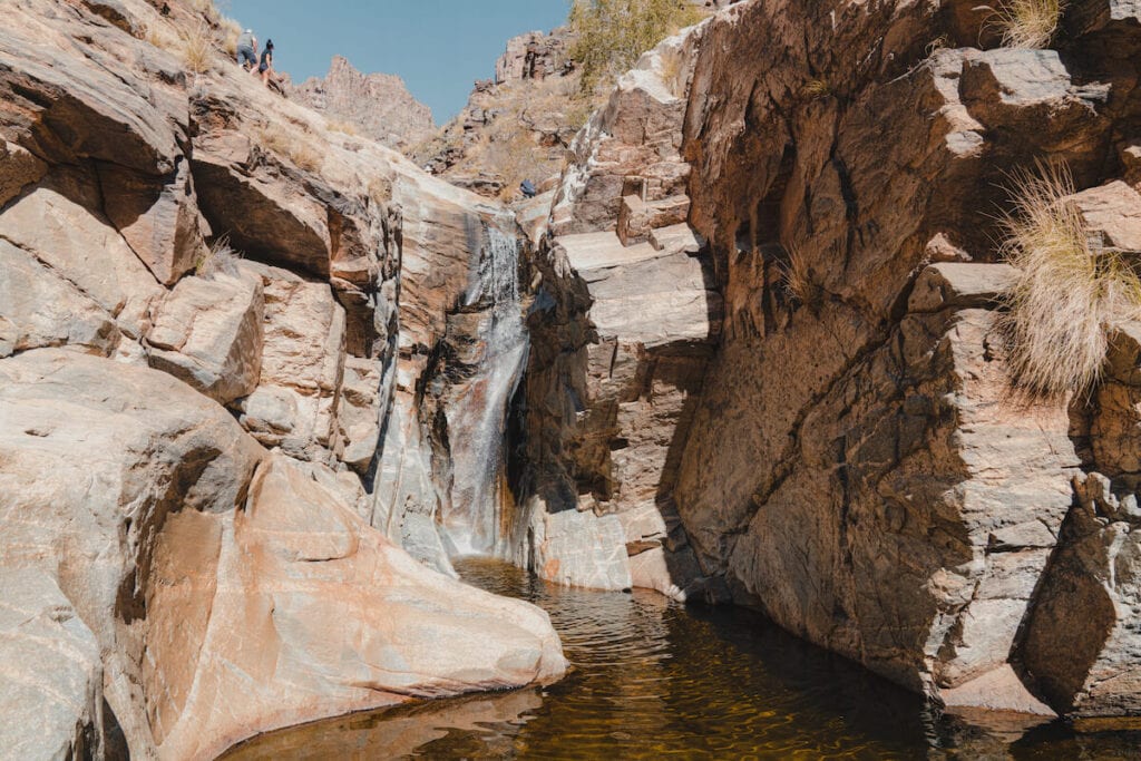 a waterfall cascades down a red rock on the Seven Falls Trail in Tucson