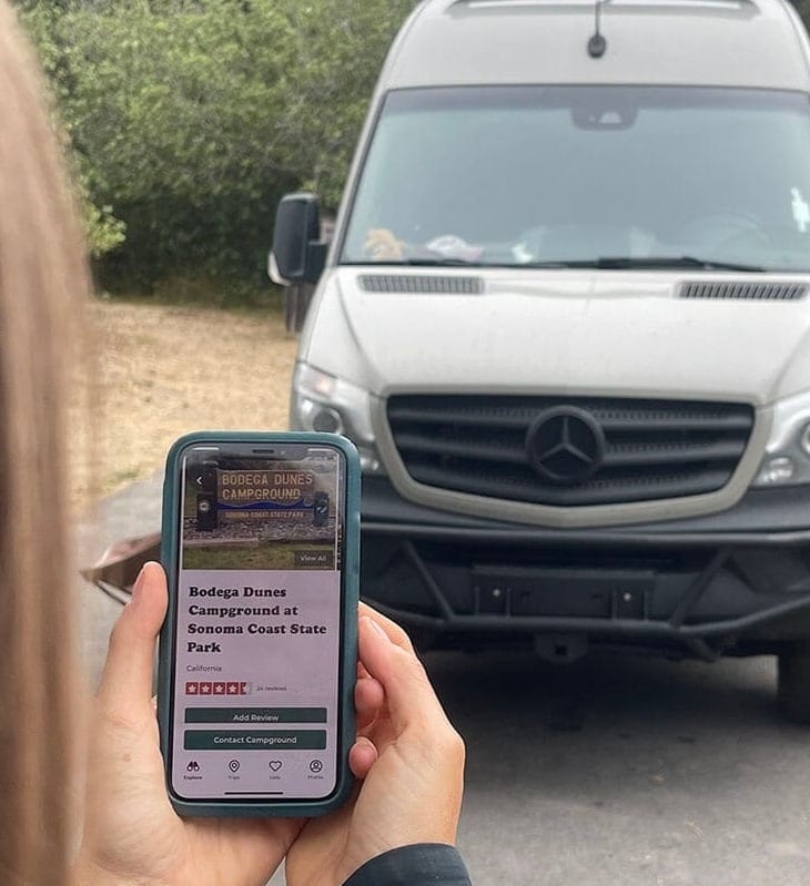 Kristen outside her camper van with The Dyrt Pro on her phone