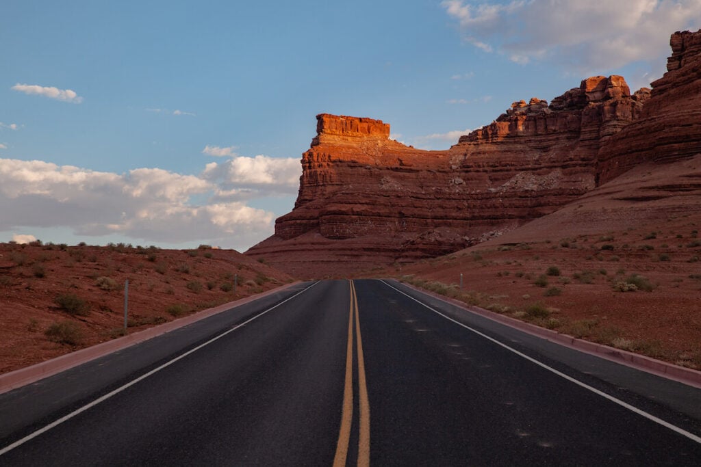 scenic drive in Utah with red sandstone cliff in the distance