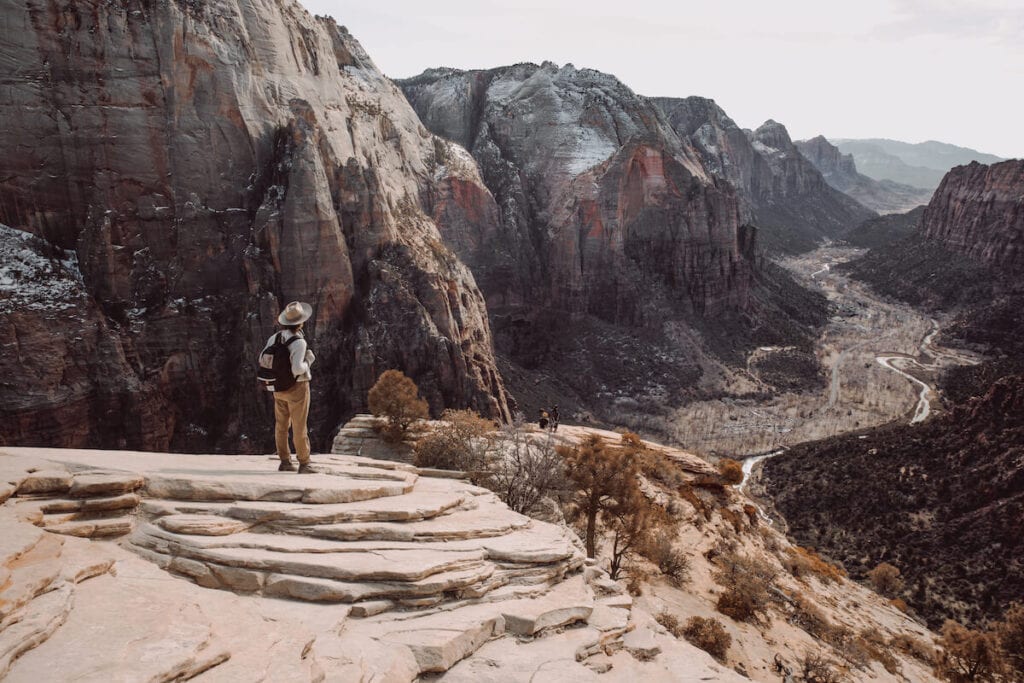 a man stands at the top of Angel's Landing in Zion National Park 