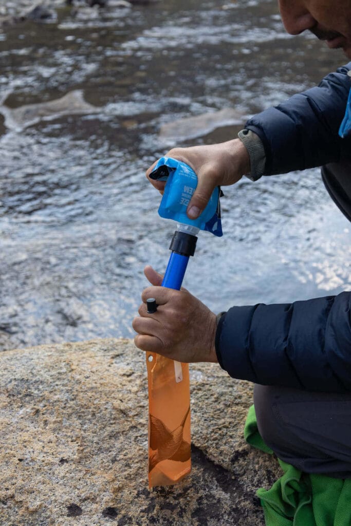 Man using Sawyer Squeeze water filler to fill up water bottle