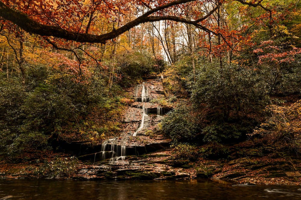 Small cascading waterfall in Smoky Mountains National Park surrounding by changing fall leaves
