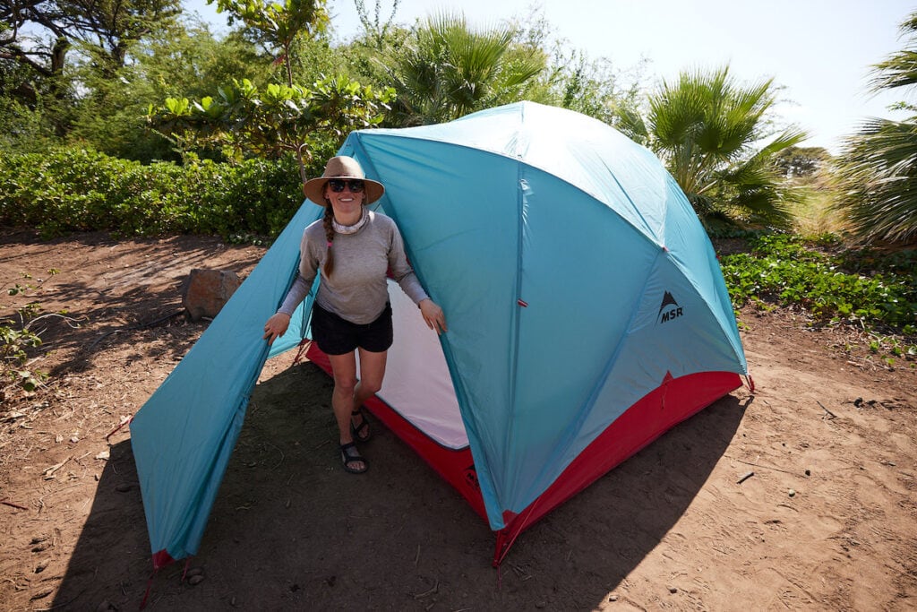 Woman standing in doorway of tent set up at campsite