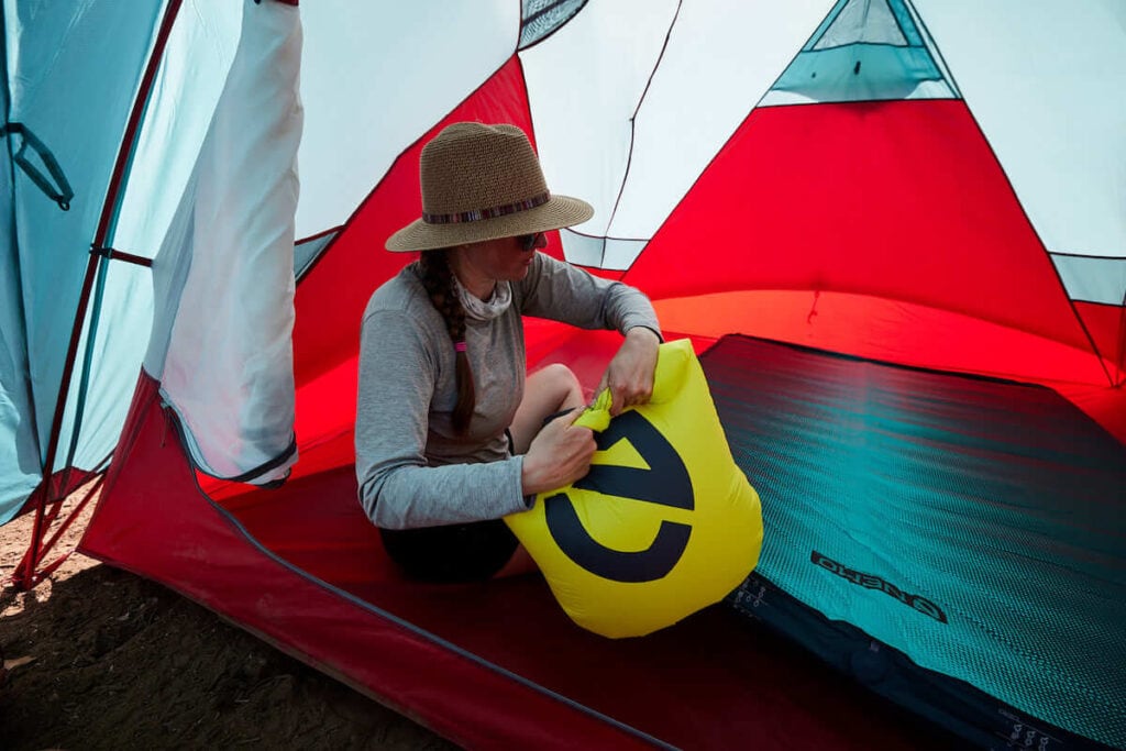 A woman uses the Vortex pump sack to inflate the NEMO Roamer Double Sleeping Pad