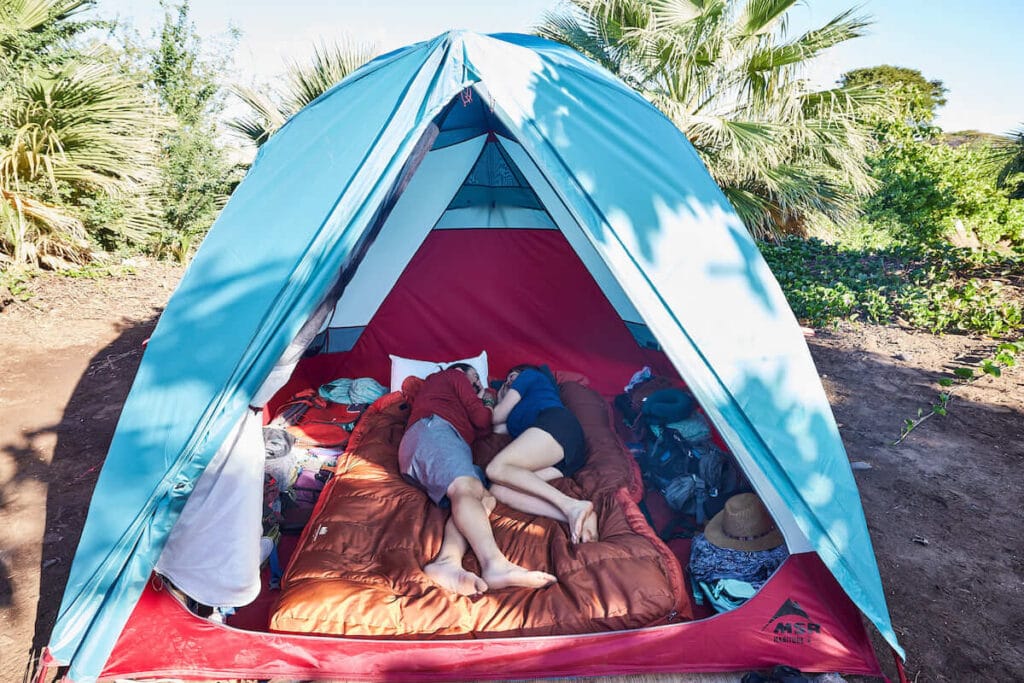 A man and woman lay on a sleeping bag on top of the NEMO Roamer Double Sleeping Pad inside a camping tent