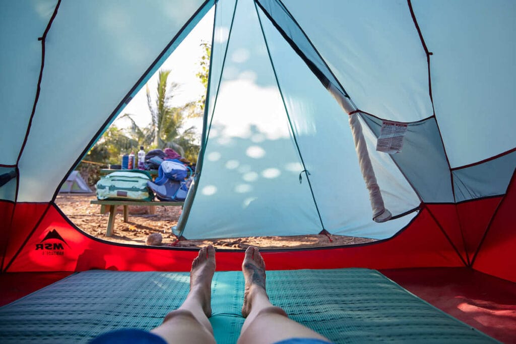 A woman lays on top of the NEMO Roamer Double Sleeping Pad inside a camping tent